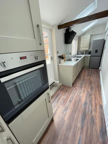 a kitchen with white cabinets and a wooden floor at Georgian 3 bed house in historic town centre in Shrewsbury