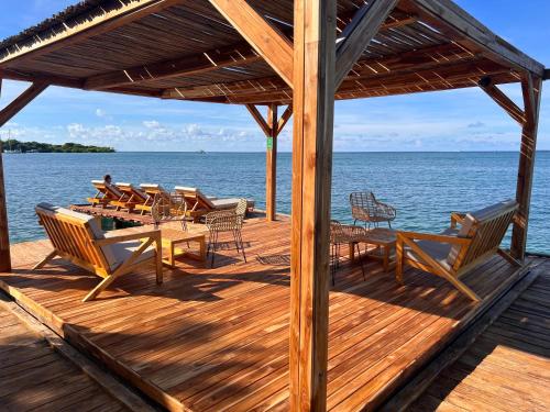 una terrazza in legno con tavoli e sedie sull'acqua di Rosario EcoHotel a Isla Grande