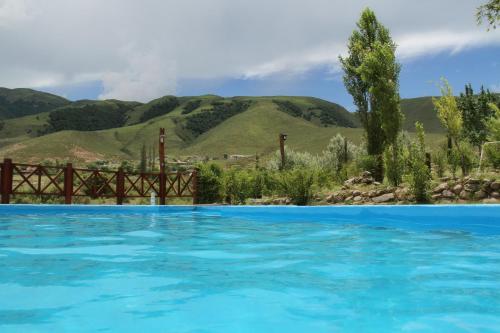 una piscina azul con montañas en el fondo en Posada La Guadalupe en Tafí del Valle
