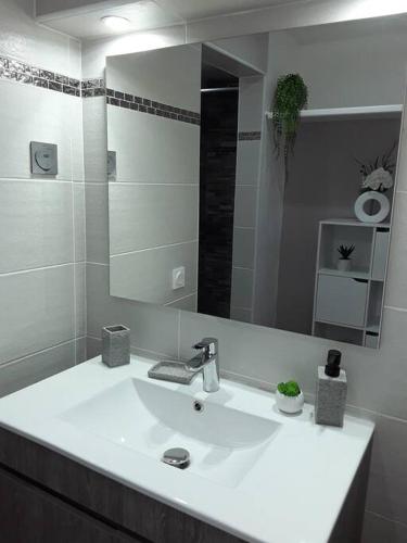 a white bathroom with a sink and a mirror at La Perle du Rocher in Le Diamant