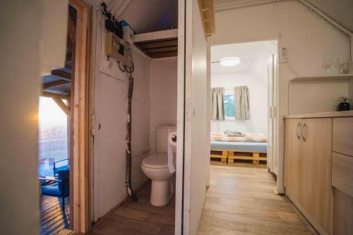 een badkamer met een toilet en een kamer met een bed bij Maringotka Olívie v Ivančicích in Ivančice