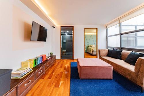 a living room with a couch and a tv at Stylish apartment with private roof top & jacuzzi in Mexico City