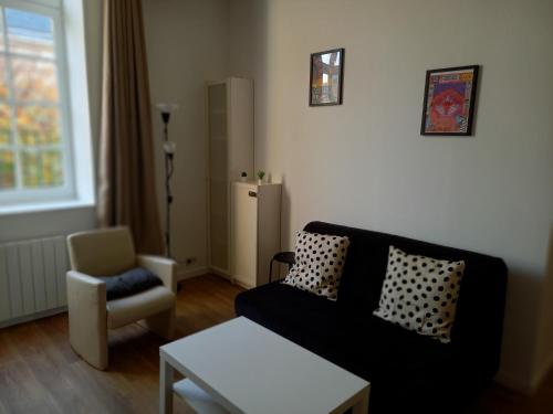salon z czarną kanapą i krzesłem w obiekcie Le Fayolle - Lumineux 2 pièces en centre-ville w mieście Dieppe