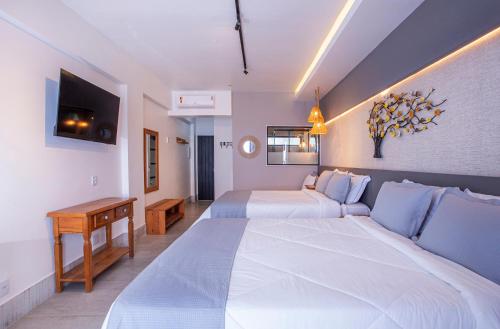 a hotel room with two beds and a television at Hotel Village Enseada in Ubatuba