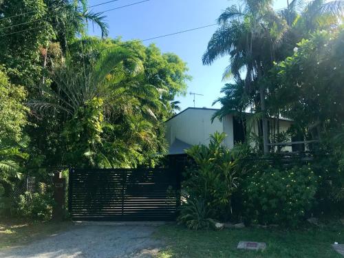 a gate in front of a house with palm trees at Elevated Tropical House in Casuarina