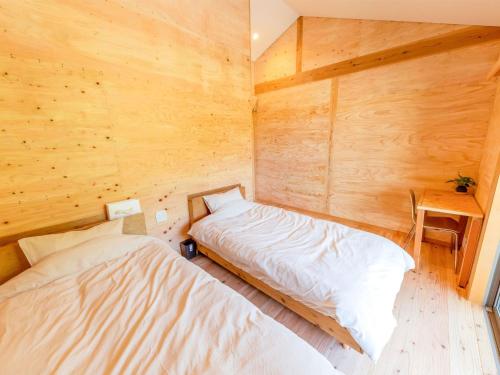 twee bedden in een kamer met houten wanden bij Guest House Amami Long Beach 2 - Vacation STAY 64482v in Amami