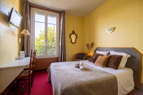 a bedroom with a bed and a desk and a window at Montdidier Hôtel in Montdidier