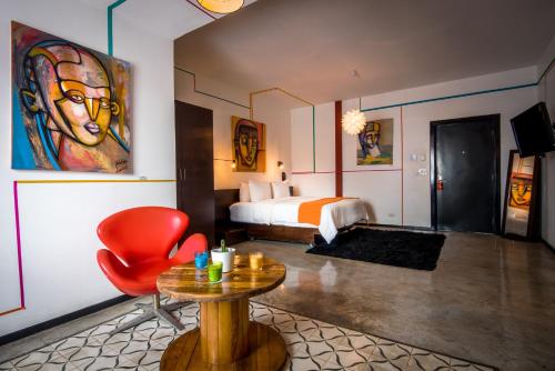 um quarto de hotel com uma cama, uma mesa e uma cadeira vermelha em Tantalo Hotel - Kitchen - Roofbar na Cidade do Panamá