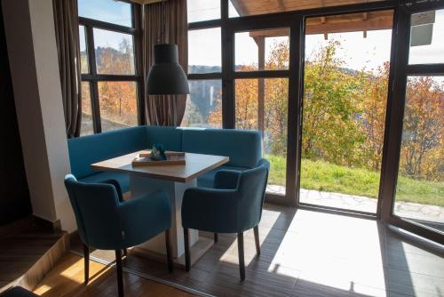 a dining room with a blue couch and a table and windows at Apartman Andjela in Kopaonik
