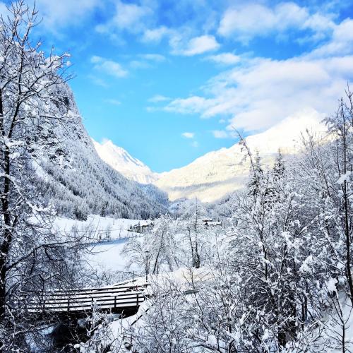 a bridge in a snow covered valley with a mountain at Bauernhof Stempf in Heiligenblut