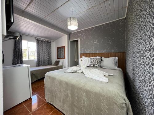 Un dormitorio con una cama con una manta blanca. en Pousada Arco Íris, en Urubici