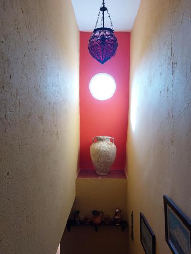 a hallway with a red wall and a chandelier at Mirador del farmacéutico in Zahara de la Sierra