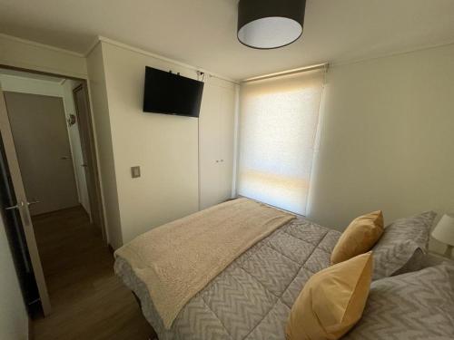 a bedroom with a bed and a television on the wall at Departamento Nuevo Papudo - Full equipado - 7 personas in Papudo