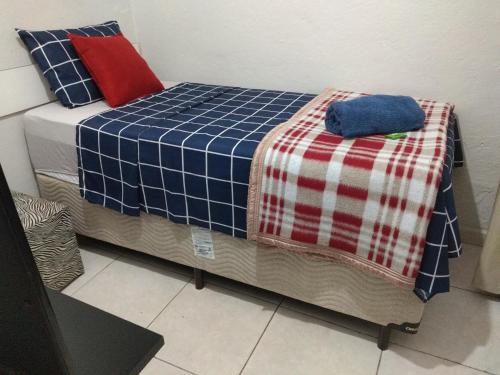 a bed with a blue and red blanket on it at Recanto do Parque in Campo Grande