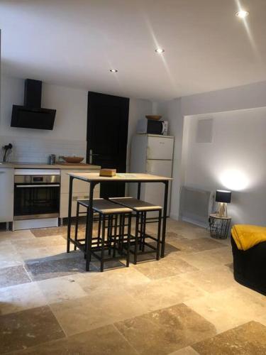 une cuisine avec une table et quelques chaises dans l'établissement Bienvenue « À l’ombre du figuier », à Pieusse