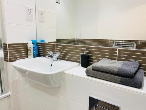 Baño blanco con lavabo y espejo en Spacious two Bedroom Apartment in Balham, en Londres