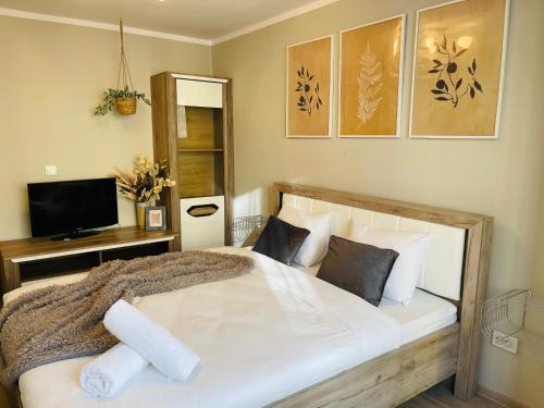 een slaapkamer met een groot wit bed en een televisie bij Hygge place to stay - self check in nonstop 24h-wifi in Reşiţa