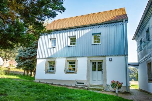 a white house with a blue roof at Traumhaftes Gästehaus an Elberadweg und Bastei in Rathen