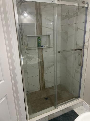 a shower with a glass door in a bathroom at Stunning & cozy freshly renovated 2 bedroom basement unit in Kitchener