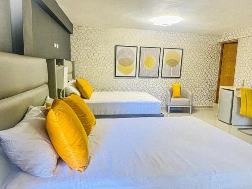 a hotel room with two beds with yellow pillows at El Paso Hotel 