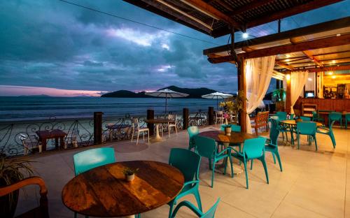 a restaurant with tables and chairs and a view of the ocean at Hotel Village Enseada in Ubatuba