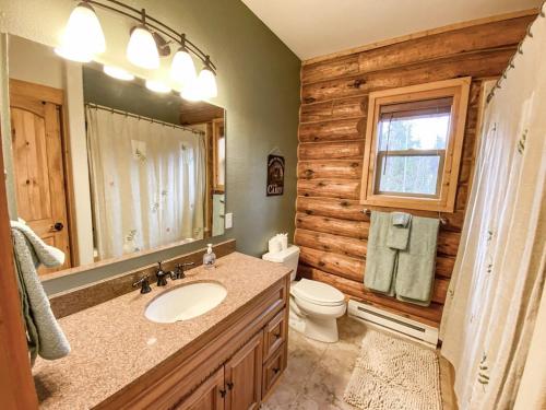 a bathroom with a sink and a toilet and a mirror at Secluded Log Cabin with Views & Hot Tub, Foosball, Wood Stove - Heavenly Homestead in Fairplay