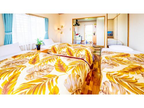 two beds in a room with yellow and orange blankets at Hotel Sunset Zanpa - Vacation STAY 50201v in Tokeshi