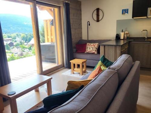 a living room with a couch and a kitchen at Plein Soleil Modern 3 bedroom apartment with stunning mountain views in Samoëns