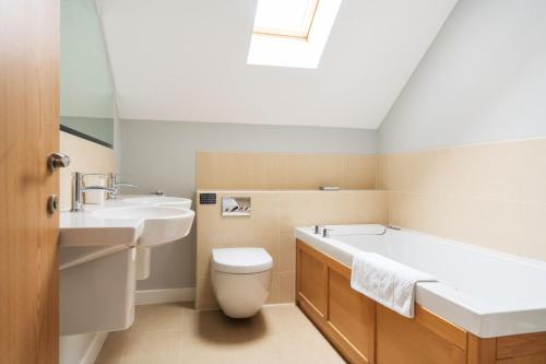 a bathroom with a tub and a toilet and a sink at KingFisher Hot Tub & log Burner house on Premium lakeside with Resort Facilities in Saint Columb Major