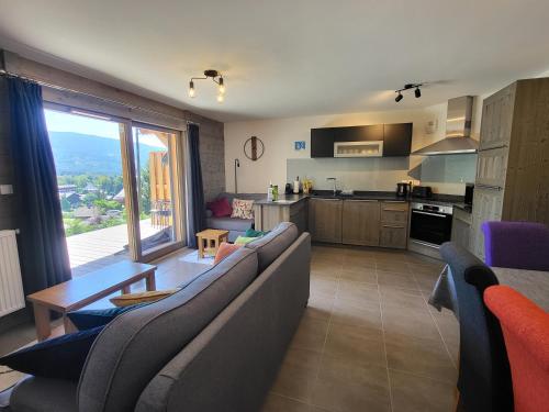 un salon avec un canapé et une table et une cuisine dans l'établissement Plein Soleil Modern 3 bedroom apartment with stunning mountain views, à Samoëns