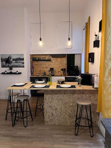 une cuisine avec un comptoir et un bar avec tabourets dans l'établissement Charmant appartement climatisé aux pieds de la cité, à Carcassonne