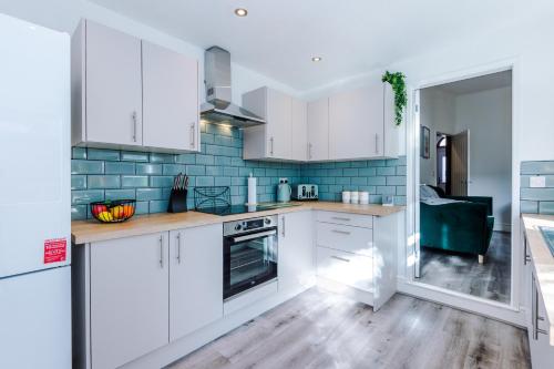 una cucina con armadi bianchi e piastrelle blu di Spacious 4-bed house in Crewe by 53 Degrees Property, ideal for Business & Contractors - Sleeps 7 a Crewe