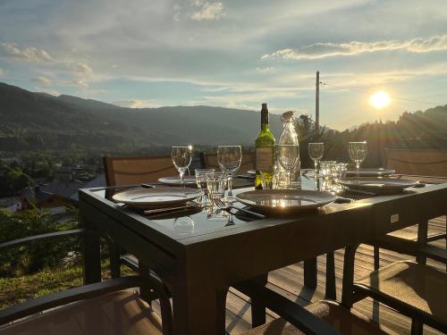 a table with wine glasses and wine bottles on a balcony at Plein Soleil Modern 3 bedroom apartment with stunning mountain views in Samoëns