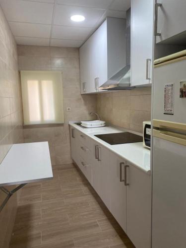 uma cozinha com armários brancos e uma bancada em CASA PAULA em Múrcia