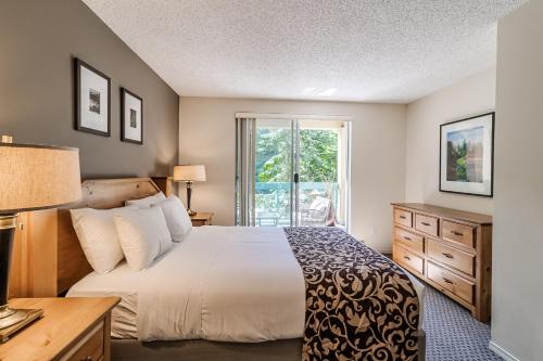 um quarto com uma cama grande e uma janela em Snowbird by Elevate Vacations em Whistler