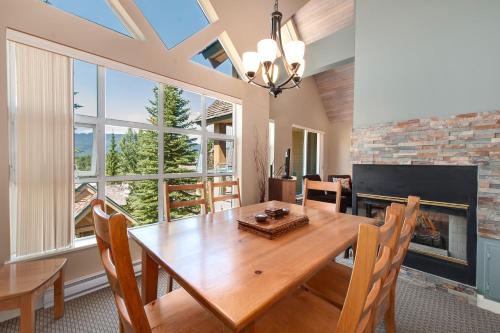 a dining room with a wooden table and a fireplace at Snowbird by Elevate Vacations in Whistler