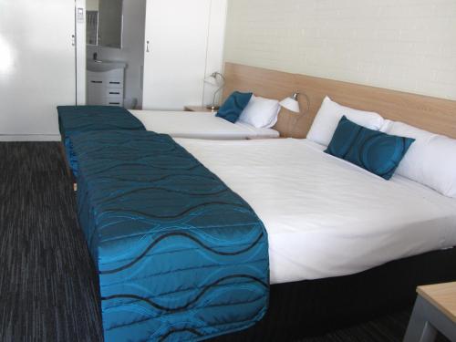 two beds in a hotel room with blue pillows at Urangan Motor Inn in Hervey Bay