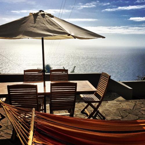 a table and chairs with an umbrella and the ocean at Casa da Ovelha I Madeira in Fajã da Ovelha