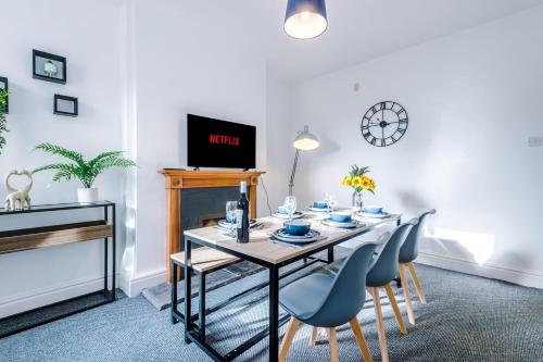 comedor con mesa, sillas y reloj en Spacious 3-Bed house in Stoke by 53 Degrees Property, Ideal for Long Stays, FREE Parking - Sleeps 6, en Stoke on Trent