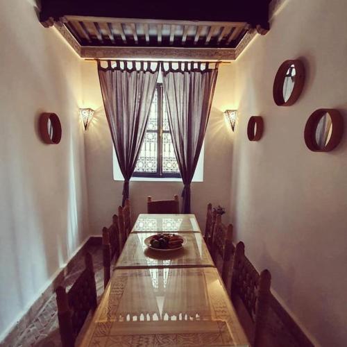 a dining room with a long table and a window at Charmant riad pour familles ou groupes - Dar Mama in Essaouira