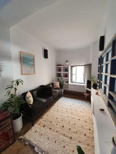 a living room with a black couch and a rug at Charmant riad pour familles ou groupes - Dar Mama in Essaouira