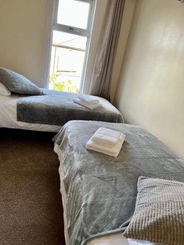two beds in a room with a window at Victorian house between cathedral, river and station in Ely