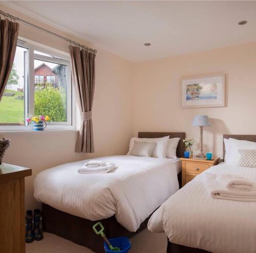 a bedroom with two beds and a window at Skylark sleeps 8 private Hot Tub & Dogs welcome Nr Padstow, Resort Pool Bar & Watersports in Saint Columb Major