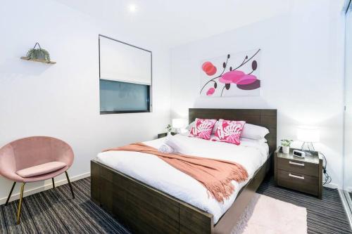 um quarto com uma cama e uma cadeira rosa em Trendy 2 bed 2 bath Apartment - Heart of St Kilda em Melbourne