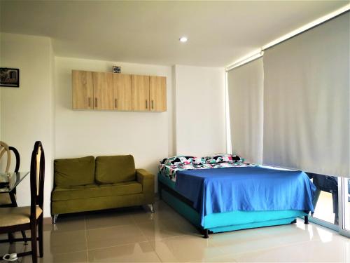 a bedroom with a bed and a chair and a window at Apartment cerca centro histórico Sta Fe Antioquia in Santa Fe de Antioquia