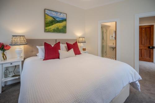 a bedroom with a white bed with red pillows at French Bay House in Akaroa