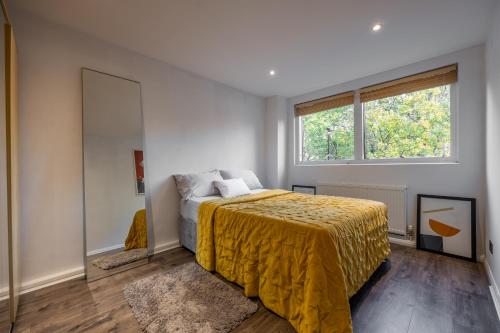 una camera da letto con un letto con copriletto giallo e una finestra di Nino Homes Kings cross a Londra