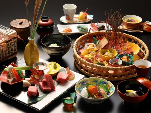 a table topped with plates of food and baskets of food at Hotel Tamanoyu in Matsumoto