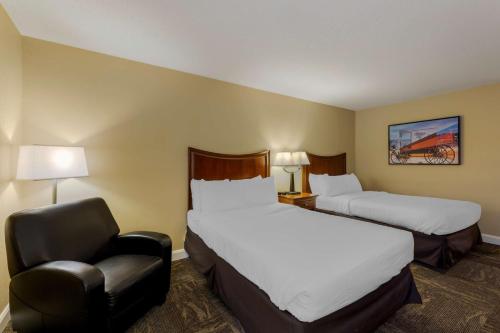 a hotel room with two beds and a chair at Best Western Plus Wooster Hotel & Conference Center in Wooster