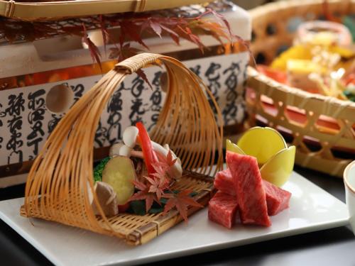 a basket of food on a plate on a table at Hotel Tamanoyu in Matsumoto